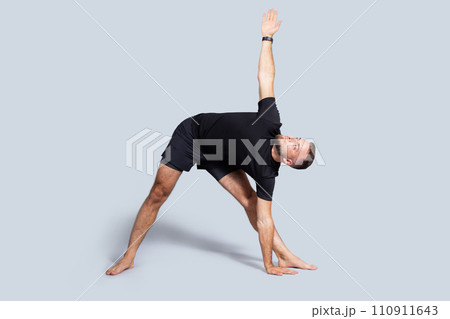Calm handsome millennial european guy with beard in sportswear practice yoga, breath exercises, stretching body 110911643