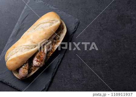 Traditional choripan, Argentina sandwich with chorizo and chimichurri sauce on black slate background Traditional choripan, Argentina sandwich with chorizo and chimichurri sauce on black slate background 110911937