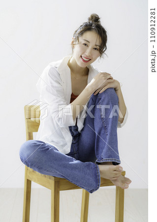 椅子に座る若い女性の全身のポートレート　縦位置 110912281