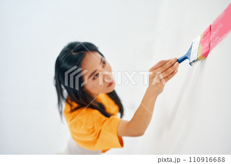 Young asian woman painting interior wall with paintbrush in new house. Young asian woman painting interior wall with paintbrush in new house. 110916688