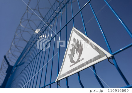 A fence with barbed wire and a triangle sign is extremely flammable. SDOF 110916699