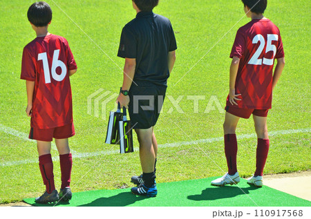 少年サッカーの試合（選手交代準備をする選手と第4審判） 110917568