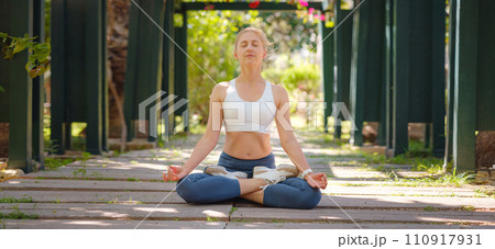 idea of healthy lifestyle and sports in a modern city. Female jogger. Fit young Caucasian woman stretching muscle in park before running and enjoying healthy outdoor. Fitness girl in public park. 110917931