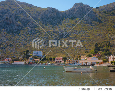 View on Symi or Simi island harbor port, classical ship yachts, houses on island hills, Aegean Sea bay. Greece islands holidays vacation travel tours from Rhodos island. Symi, Greece, Dodecanese. 110917940