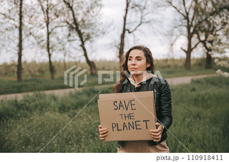 Beautiful young woman holding a banner with the text Save the planet. Beautiful young woman holding a banner with the text Save the planet. 110918411