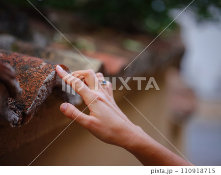 Female hand gently touches weathered tiles in old town of Kalechi, Antalya. tactile connection with ancient rooftops echoes rich history of surroundings Female hand gently touches weathered tiles in old town of Kalechi, Antalya. tactile connection with ancient rooftops echoes rich history of surroundings 110918715
