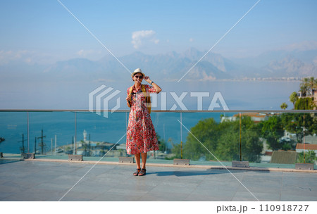 female summer travel to Antalya, Turkey. young asian woman in red dress walk through old town Kalechi , Panoramic view of Antalya Old Town port, Taurus mountains and Mediterrranean Sea, Turkey 110918727