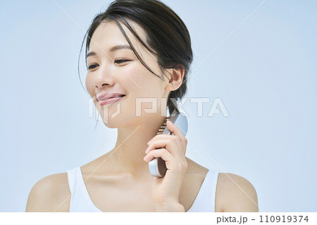 美容向けの電化製品を使ってセルフマッサージをする女性 110919374