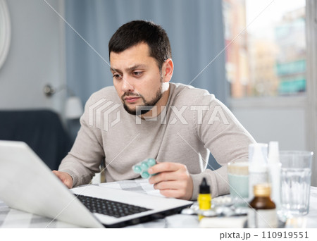 Young man looking for information about medicines on laptop Young man looking for information about medicines on laptop 110919551