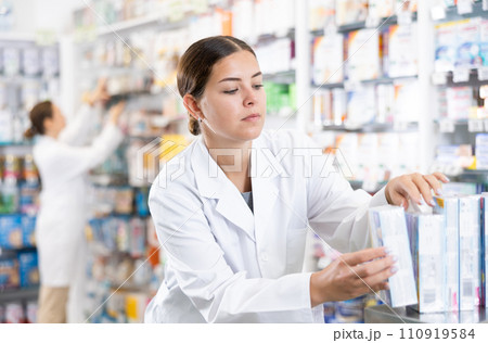 Young female pharmacist arranges product in pharmacy Young female pharmacist arranges product in pharmacy 110919584