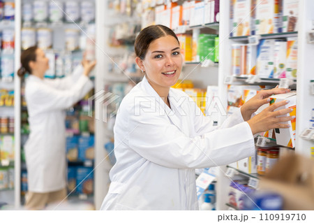 Woman seller puts medical cosmetics and other body care products on shelves 110919710