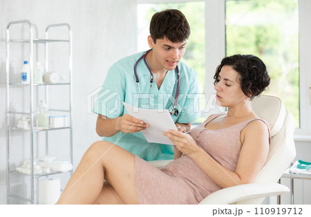 Friendly cosmetologist doctor offers woman patient to sign contract before the operation in beauty clinic 110919712