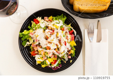spanish lettuce salad with sauce and bacon in black plate for dinner spanish lettuce salad with sauce and bacon in black plate for dinner 110919755