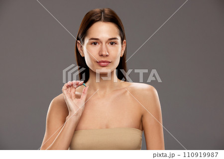 Portrait of beautiful young woman hosing skin moisturizing ampule against studio background 110919987
