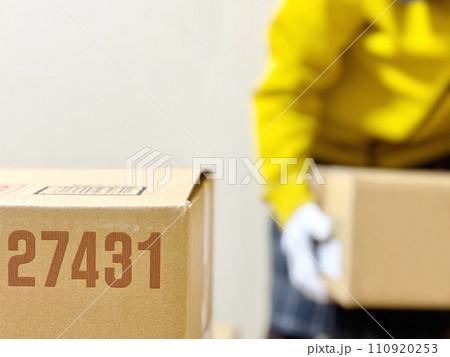 段ボールの向こうで段ボール箱を運ぶ軍手の人 110920253