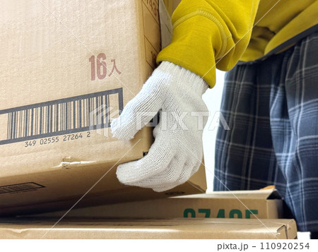 段ボールを持ち上げる軍手をはめた手のアップ 110920254
