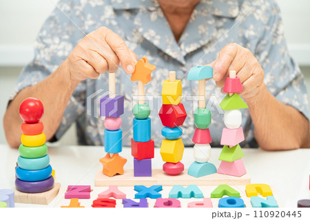 Alzheimer disease AD, Asian elderly woman patient suffering from dementia learn practical motor skills rehabilitation. Alzheimer disease AD, Asian elderly woman patient suffering from dementia learn practical motor skills rehabilitation. 110920445