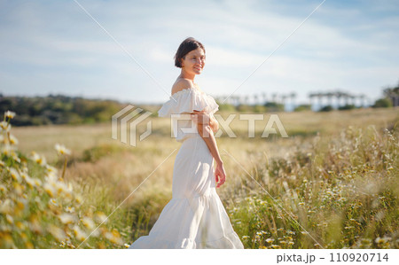 Beautiful Asian young woman in white dress outdoor in flower field. embracing fresh air and engaging in outdoor activities. Friluftsliv concept means spending as much time outdoors as possible Beautiful Asian young woman in white dress outdoor in flower field. embracing fresh air and engaging in outdoor activities. Friluftsliv concept means spending as much time outdoors as possible 110920714