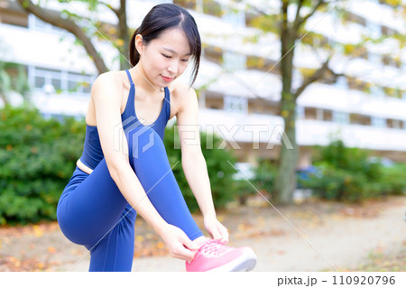 野外で運動前に靴紐を結ぶ若い女性　ボディメイク　レギンス 110920796