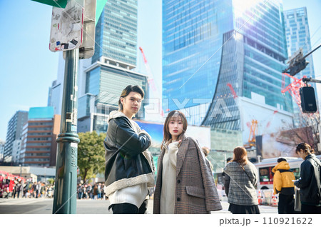 渋谷の街をバックに立つ若いカップル 110921622
