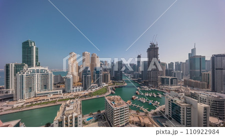 Dubai Marina with several boats and yachts parked in harbor and skyscrapers around canal aerial all day timelapse. 110922984
