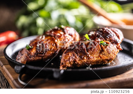 Marinated grilled chicken breast in BBQ sauce and served on a cast iron pan - Close up Marinated grilled chicken breast in BBQ sauce and served on a cast iron pan - Close up 110923256