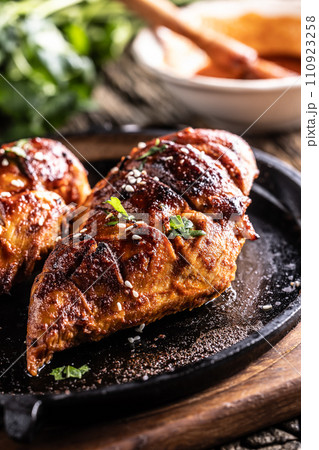 Marinated grilled chicken breast in BBQ sauce and served on a cast iron pan - Close up Marinated grilled chicken breast in BBQ sauce and served on a cast iron pan - Close up 110923258