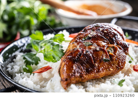 Grilled chicken breast served in a pan with jasmine rice and chili peppers Grilled chicken breast served in a pan with jasmine rice and chili peppers 110923260