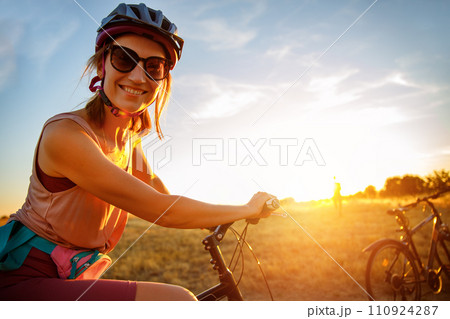 Portrait of young adult fit sporty smiling caucasian woman enjoy riding cross country bike on hay dry field in warm sunset sunlight evening morning. Healthy recreation lifestyle leisure time 110924287