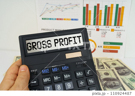 On the table there are financial reports, dollars, in the hands of a calculator with the inscription - gross profit 110924487