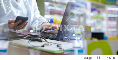 The hand of a pharmacist working with a mobile phone and laptop. The hand of a pharmacist working with a mobile phone and laptop. 110924816
