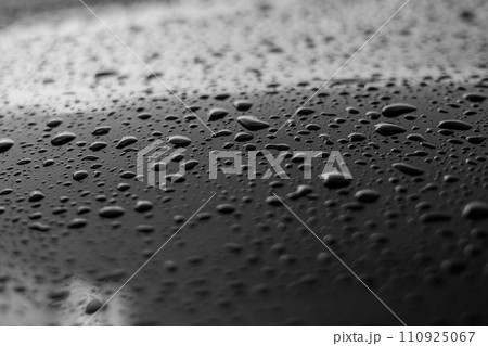 Rain or water drops different size on a black shiny car hood surface. Water droplets on dark iron surface and texture. Abstract background and water texture for design. 110925067