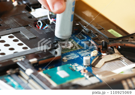 Hand a repairman uses thermal paste syringe apply thermal compound to a CPU. Master replaces thermal grease. Professional service and repair tech and electronics devices, laptops and PC 110925069