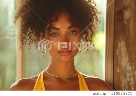 AI-generated content. Close-up portrait of a young African American woman wearing yellow sports top in a cozy home terrace. Attractive black girl with afro hairstyle and confident look. Outdoor 110925276