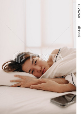 Sad and depressed Asian woman lying awake in the morning to weak to get up form bed. 110929214