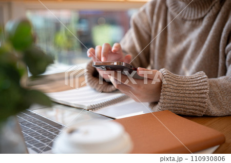 Cropped shot of a woman using her smartphone at a table at a cafe co-working space. 110930806