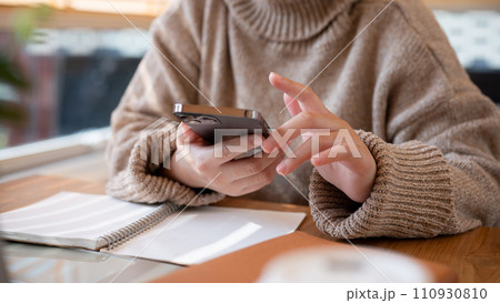 Cropped shot of a woman using her smartphone at a table at a cafe co-working space. 110930810