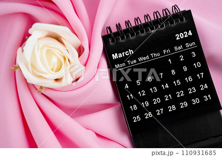 March 2024 desk calendar black color and rose on pink textile. 110931685