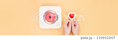 Hands holding heart shape red gift card next to white cd player with red disc on yellow background. Love music, Valentine day, Greeting, retro Love song, space for text. Hands holding heart shape red gift card next to white cd player with red disc on yellow background. Love music, Valentine day, Greeting, retro Love song, space for text. 110932047