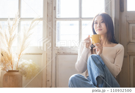 部屋でホットドリンクを飲む女性 部屋でホットドリンクを飲む女性 110932500