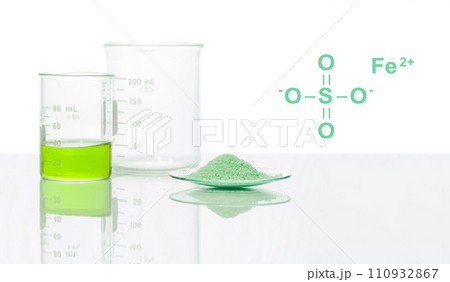 Ferrous Sulfate in chemical watch glass with chemical structure place next to Iron (II) sulfate liquid in Beaker. Side View 110932867