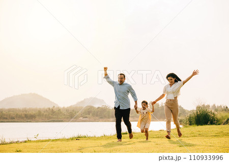 Happy family running through a beautiful green field on a sunny summer day, enjoying the freedom and beauty of nature together, Happy Family Day Concept 110933996