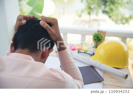 Asian young engineer man stress and failure in architecture project sitting at office on construction site. Upset despair civil construction engineer working on laptop with stressed problems 110934252