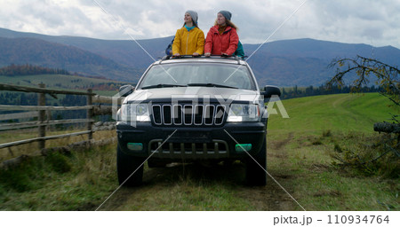 Hikers standing up through sunroof sing, dance and wave hands 110934764