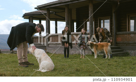 Couple with kids walks near house, plays with dogs on lawn Couple with kids walks near house, plays with dogs on lawn 110934901