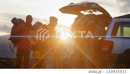 Hikers packs backpacks into trunk of car preparing for hike in mountains Hikers packs backpacks into trunk of car preparing for hike in mountains 110935011