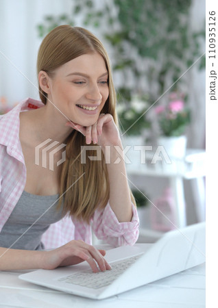 Portrait of young woman using laptop at home Portrait of young woman using laptop at home 110935126