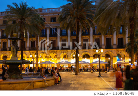 Citizens and tourists stroll and relax in cafe in light of streetlight on Royal square in Barcelona. Citizens and tourists stroll and relax in cafe in light of streetlight on Royal square in Barcelona. 110936049