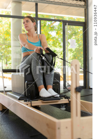 Girl stretching on pilates reformer in gym 110936447