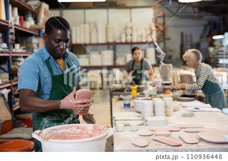 Man ceramist painting crafted plates 110936448